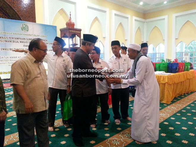 Awang Tengah presents raya contributions from Lakhir and Baitumal to representatives of a mosque in Lawas district.