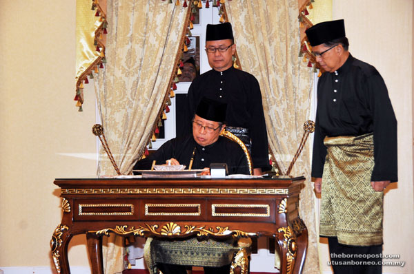 Abang Johari signs the appointment letter at the Astana in the presence of two officials.